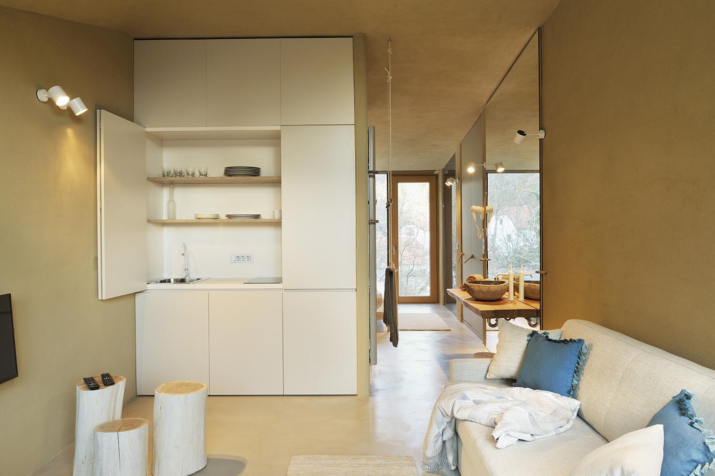 A clay-plaster interior with a forest view