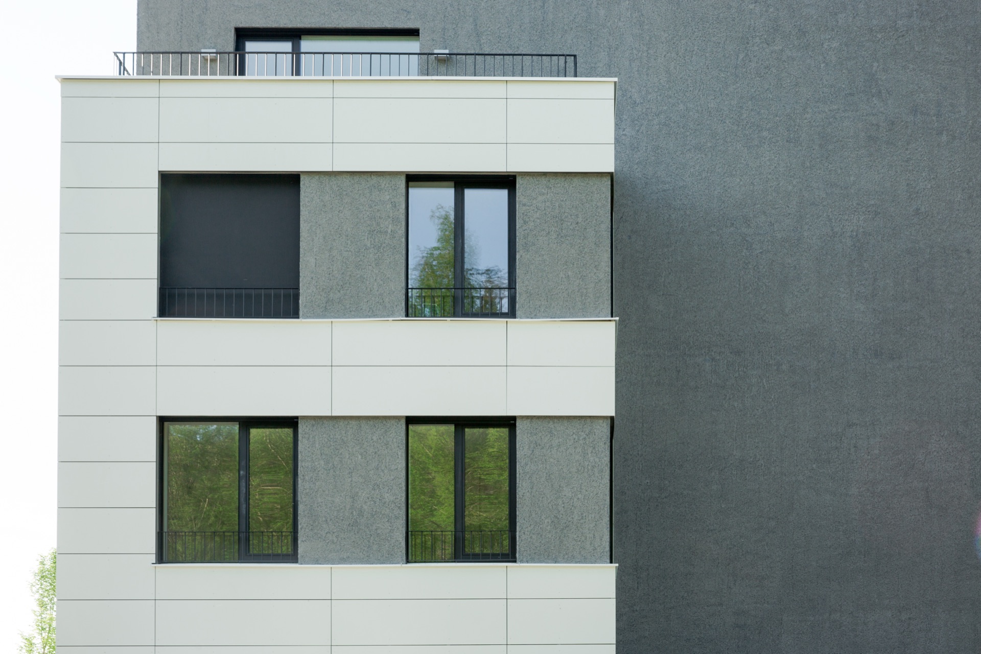 Façade detail in white panel and textured concrete