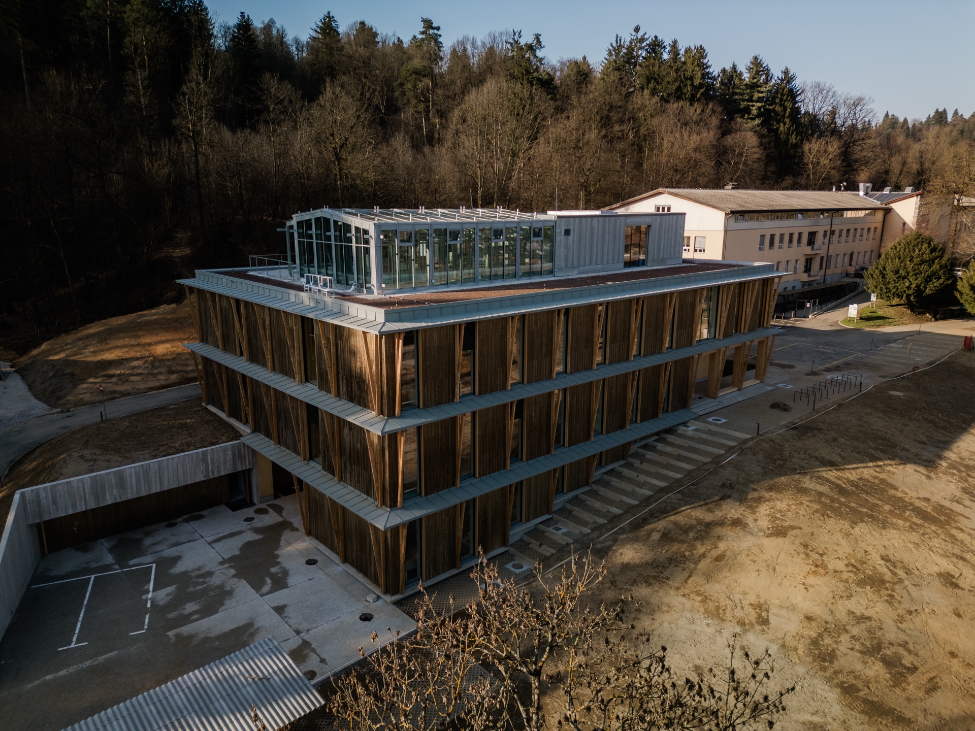 Aerial view of the timber-clad Gozdarski inštitut building set in forest